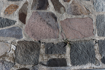 Close up to a stone wall made of colored rocks and cement