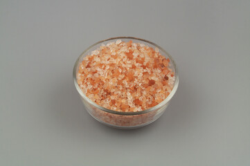 Glass bowl with himalayan pink salt on gray background