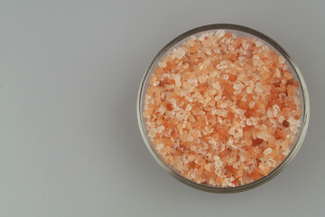 Bowl with pink Himalayan rock salt on gray background. Copy space for text.	