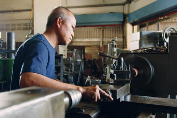 Technician asia worker using turning lathe machine for metalworking in workshop factory © Nattakorn