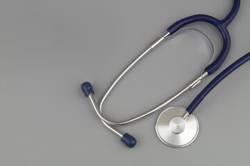 Blue stethoscope on gray background with space for text.