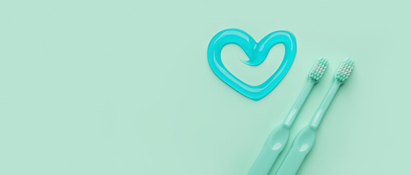 Toothbrushes and heart made of paste on turquoise background with space for text