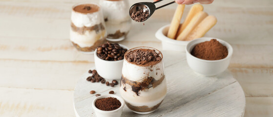 Sweet tasty tiramisu on light wooden table