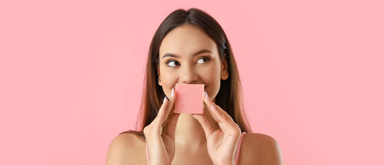 Beautiful young woman with soap on pink background