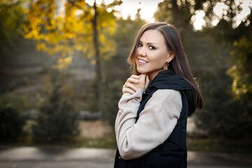 Portrait of a beautiful asian woman with brown hair in the forest in warm clothes in the fall outdoors. High quality photo