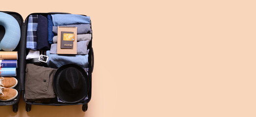 Open packed suitcase on beige background with space for text. Travel concept
