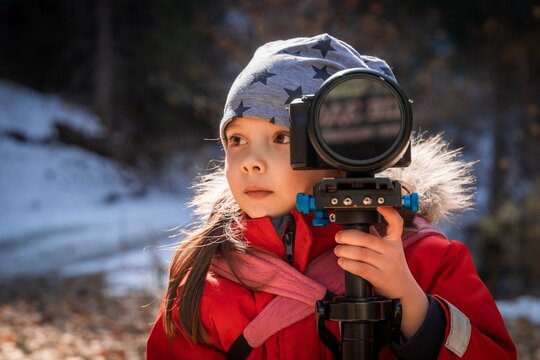 Little girl learning to take pictures with camera in nature.