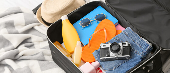 Opened suitcase with clothes and accessories for travelling on bed