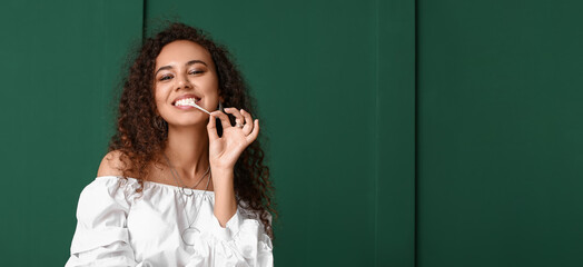 African-American woman with chewing gum on green background with space for text