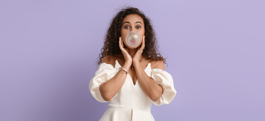 Funny African-American woman with chewing gum on lilac background