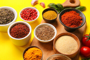Bowls of different spices on yellow background