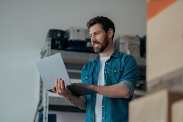 Man working laptop on warehouse with coffee machines and other professional equipments