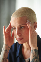 Serious businesswoman touching her head with hands having a headache after working day