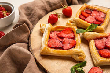 Wooden board with strawberry puff pastry on table, closeup