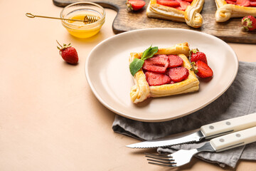 Plate with delicious strawberry puff pastry on beige table