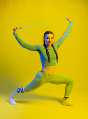 girl in a sports top and leggings. athlete in golf. Sports girl doing exercises for the buttocks with a resistance band on a yellow background. Fitness woman exercising. yellow background