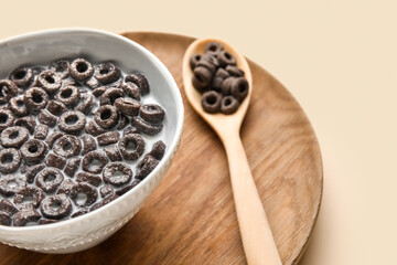 Bowl and spoon with tasty cereal rings and milk on color background, closeup