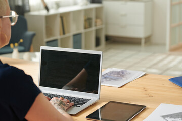 Close-up of architect working over architectural project online at home using her laptop