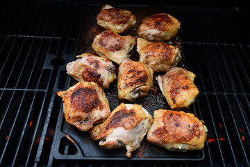 Chicken thighs grilling on a cast iron skillet.