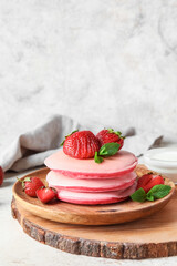 Wooden board with plate of tasty pancakes and strawberry on table, closeup