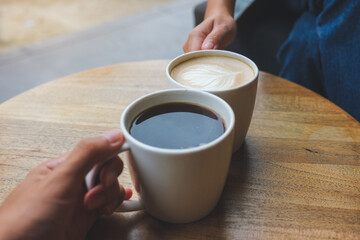 Closeup image of a couple people clinking coffee cups together in cafe