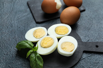Board with halves of boiled chicken eggs on dark background, closeup