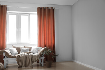 Modern couch and houseplant near red curtains in room