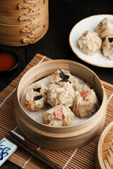 Dimsum with various toppings, served in a bamboo steamer and spicy sauce. 
