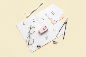 Stapler with different stationery supplies and eyeglasses on yellow background