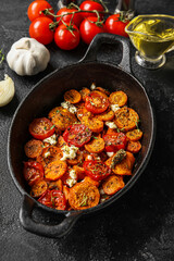Frying pan with baked vegetables on dark background