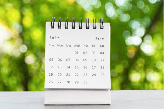 June 2022 desk calendar for planners and reminders on a black table on the natural background green .
