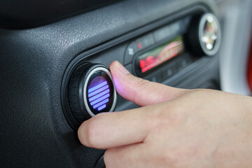 Woman hand turn on car air conditioning system