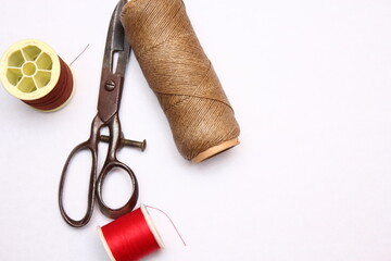 Multi-colored threads and old scissors spread out on a white floor, retro scissors, flat lay, copy space.