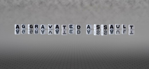 aggravated assault word or concept represented by black and white letter cubes on a grey horizon...