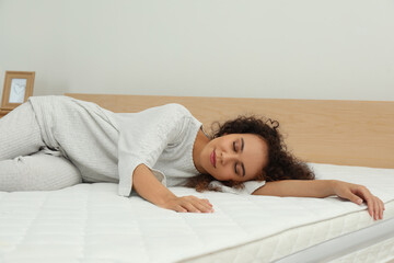 Young African American woman sleeping on bed with comfortable mattress at home