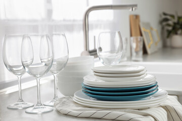 Different clean dishware and glasses on countertop near sink in kitchen