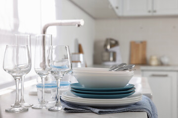 Different clean dishware, cutlery and glasses on countertop in kitchen