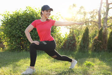 Young woman listening to music while doing morning exercise on green grass in park