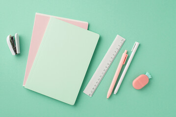 Back to school concept. Top view photo of stationery copybooks pens ruler stapler and pineapple shaped eraser on isolated pastel green background