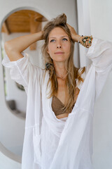 Fototapeta premium Summer portrait of beautiful blond woman in white summer clothes posing in modern hotel.