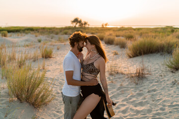 Romantic moments of beautiful couple in love posing on summer tropical beach. Sunset colors.