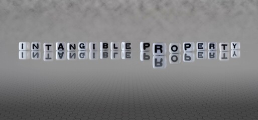 intangible property word or concept represented by black and white letter cubes on a grey horizon background stretching to infinity