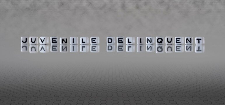 juvenile delinquent word or concept represented by black and white letter cubes on a grey horizon background stretching to infinity