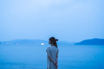 Fototapeta premium 夕暮れの海を散策する女性