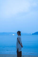 夕暮れの海を散策する女性