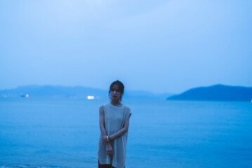 Fototapeta premium 夕暮れの海を散策する女性