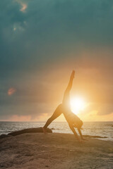 Fototapeta na wymiar Silhouette young woman does yoga position splits or twine for healthy lifestyle on tropical coast sea