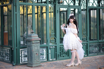 Beautiful young woman with white lolita dress with european garden Japanese fashion