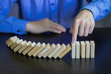 Business Risks and Strategies hand stop falling wooden block domino Consequences of falling blocks defense and development for security Prevention and problem solving concepts