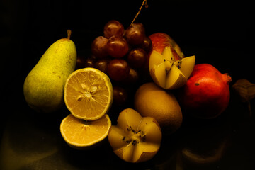 Grapes Kiwi Pear Plum Pomegranate summery  fruits on black background with it's reflection juicy fresh